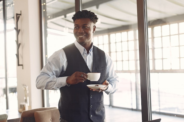 Uomo di colore in una camicia blu in piedi in un caffè