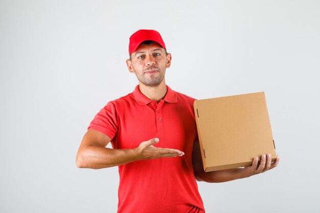 Uomo di consegna che mostra la scatola della pizza in mano in uniforme rossa