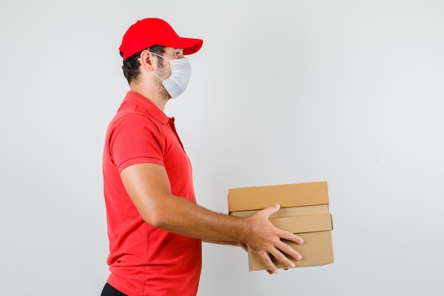 Uomo di consegna che tiene le scatole di cartone in maglietta rossa
