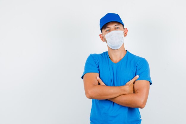 Uomo di consegna in piedi con le braccia incrociate in maglietta blu