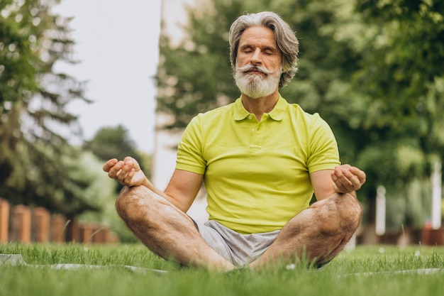 Uomo di mezza età a praticare yoga sulla stuoia nel parco