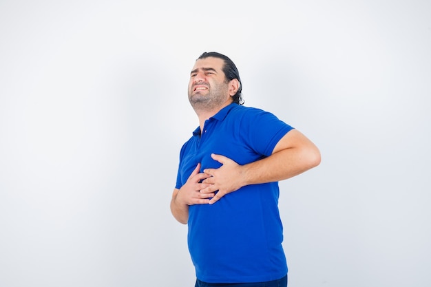 Uomo di mezza età in maglietta blu che soffre di dolore al cuore