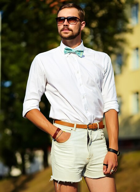 Uomo di modello bello hipster in abiti estivi alla moda in posa in occhiali da sole