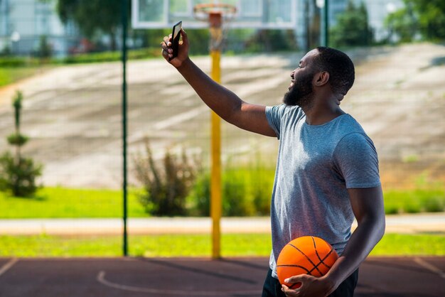 Uomo di pallacanestro afro che fa un selfie con il suo telefono
