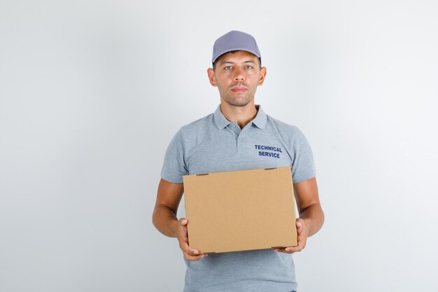 Uomo di servizio tecnico in maglietta grigia con cappuccio che tiene la scatola di cartone
