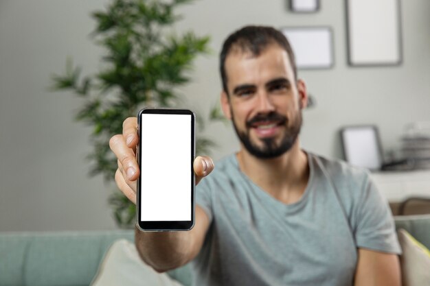 Uomo di smiley a casa che tiene smartphone