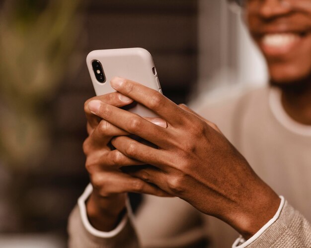 Uomo di smiley a casa utilizzando smartphone