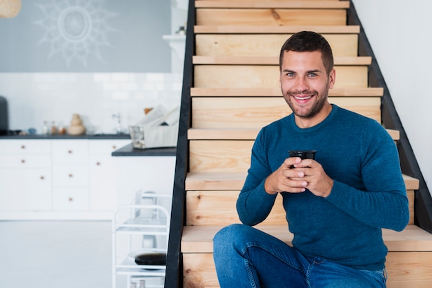 Uomo di smiley che guarda l'obbiettivo e che tiene una tazza di caffè