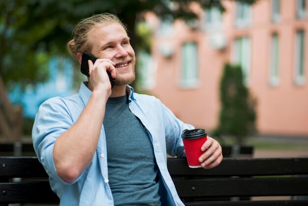 Uomo di smiley che intraprende smartphone all'aperto