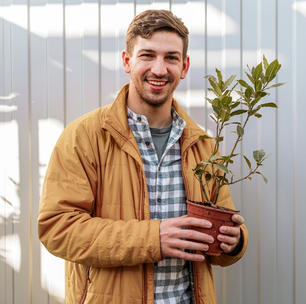 Uomo di smiley che tiene pentola con piccolo albero