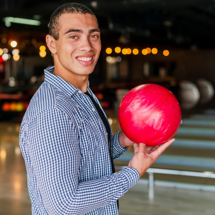 Foto gratuito uomo di smiley che tiene un colpo medio della sfera di bowling rossa