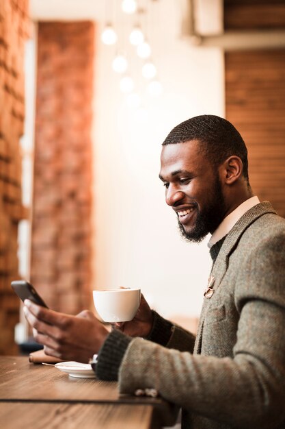 Uomo di smiley che tiene una tazza con caffè in un pub