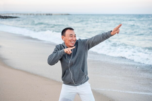 Uomo di smiley colpo medio in riva al mare