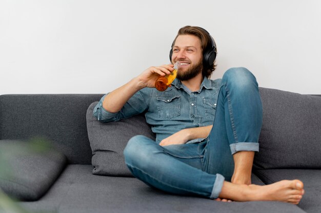 Uomo di smiley colpo pieno con drink e cuffie