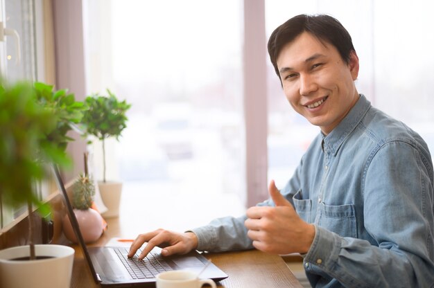 Uomo di smiley con il computer portatile che mostra segno giusto