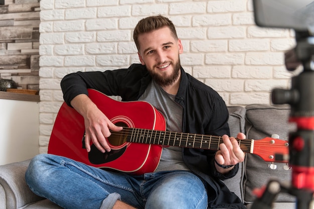 Uomo di smiley del colpo medio che gioca chitarra