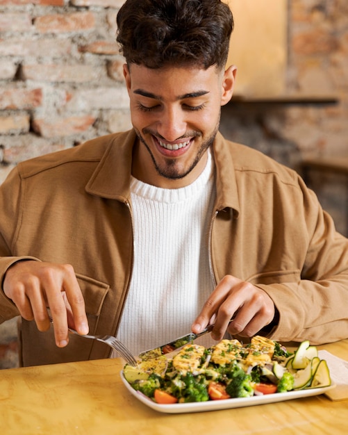 Uomo di smiley del colpo medio che mangia alimento