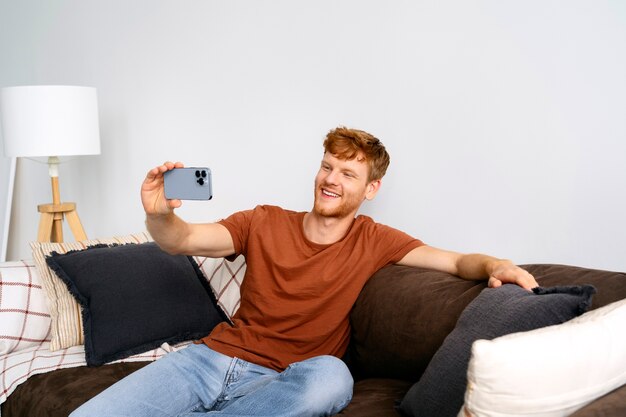 Uomo di smiley del colpo medio che prende selfie