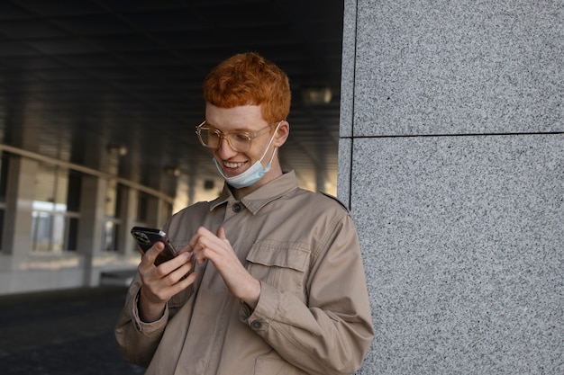 Uomo di smiley del colpo medio che tiene smartphone