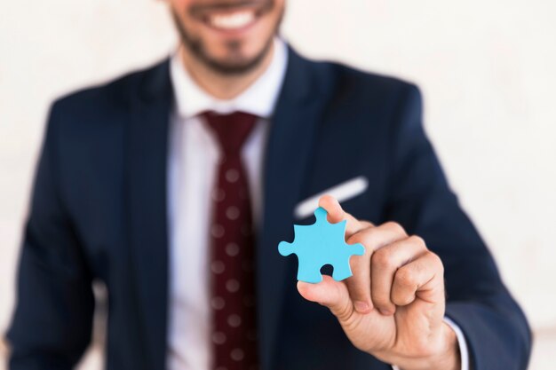 Uomo di smiley del primo piano che tiene un pezzo di puzzle