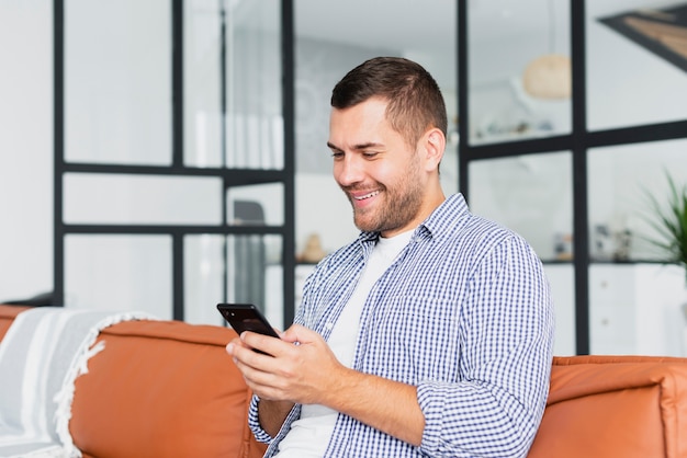 Uomo di smiley di vista frontale con lo smartphone