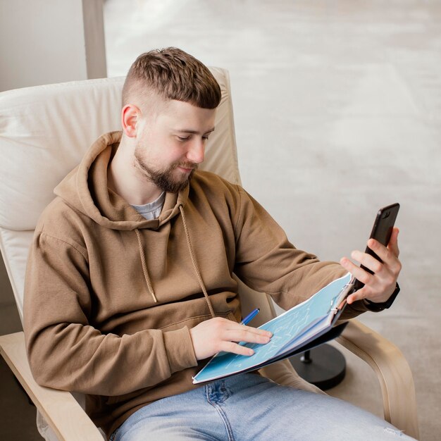 Uomo di taglio medio con uno smartphone in mano