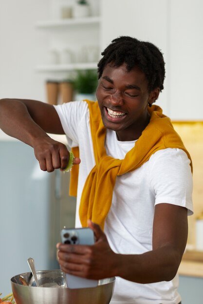 Uomo di tiro medio che cucina con lo smartphone