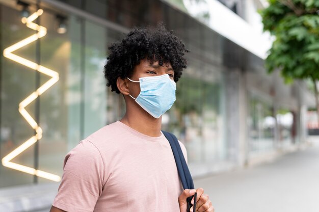 Uomo di tiro medio che indossa la maschera facciale all'aperto