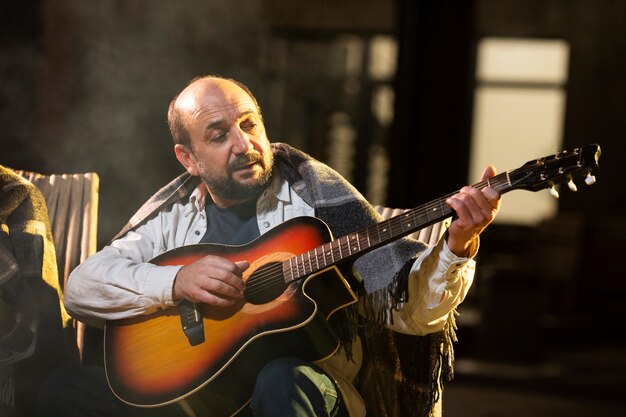 Uomo di tiro medio che suona la chitarra