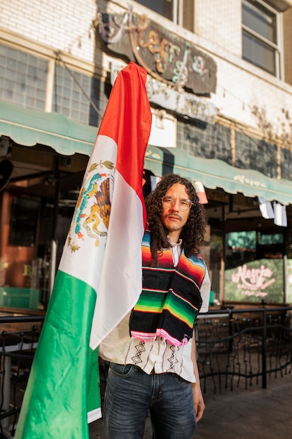 Uomo di tiro medio che tiene bandiera messicana