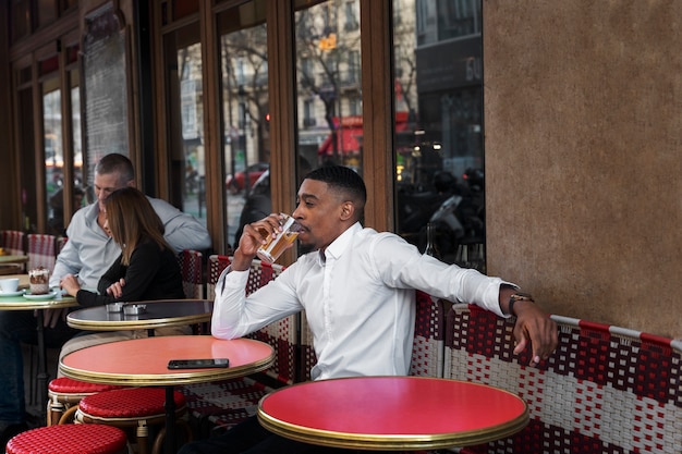 Uomo di tiro medio con drink al bistrot