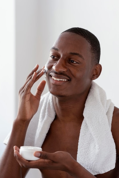 Uomo di tiro medio utilizzando crema per il viso