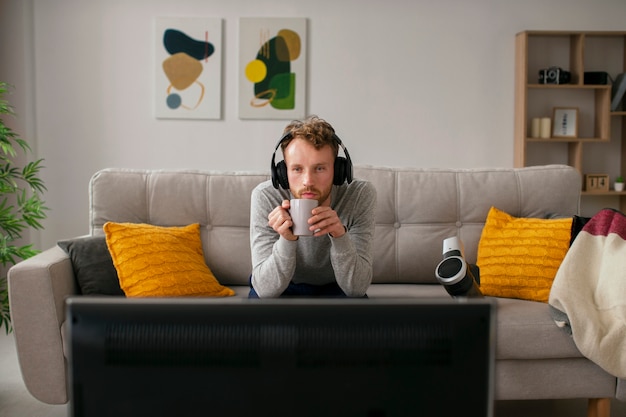 Uomo di vista frontale che guarda la tv con le cuffie