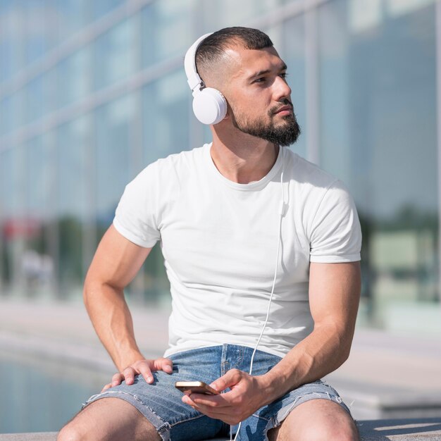 Uomo di vista frontale che guarda lontano durante l'ascolto di musica