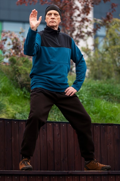 Uomo di vista frontale che pratica il tai chi all'aperto