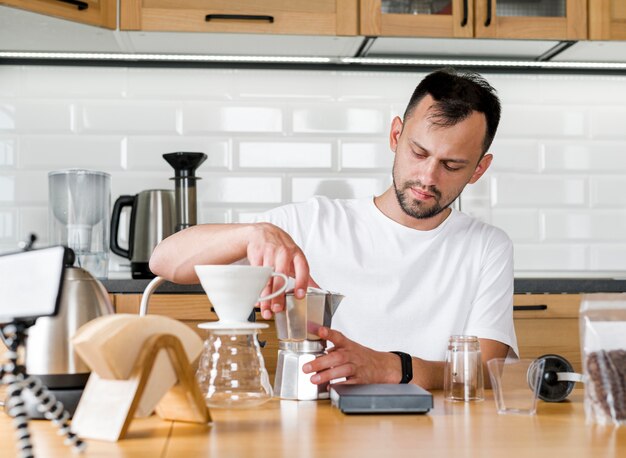 Uomo di vista frontale che produce caffè