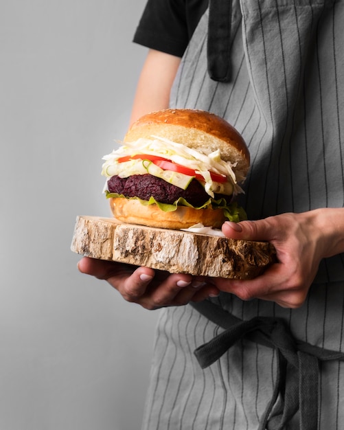 Uomo di vista frontale che tiene un hamburger su un bordo di legno