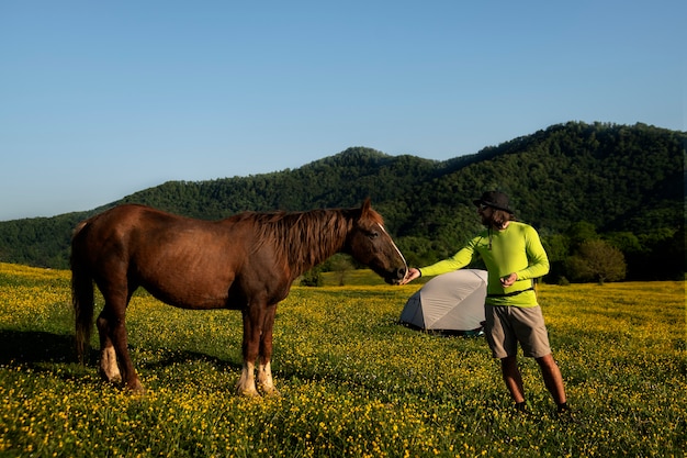 Uomo di vista laterale che alimenta cavallo selvaggio