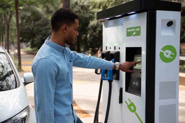 Uomo di vista laterale che carica auto elettrica