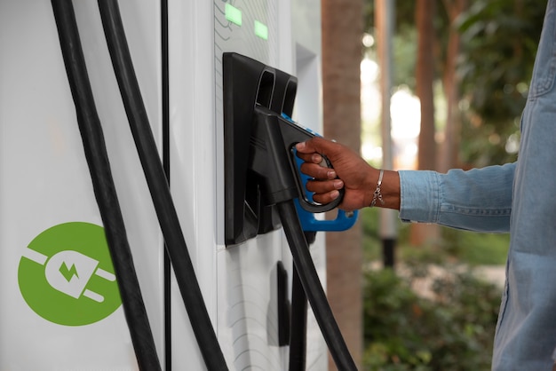 Uomo di vista laterale che carica auto elettrica