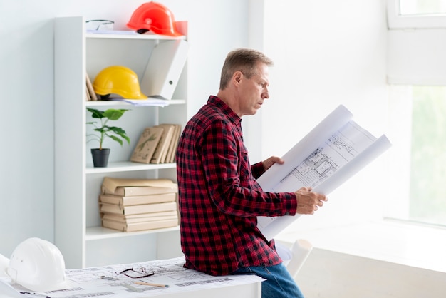 Uomo di vista laterale che controlla progetto architettonico