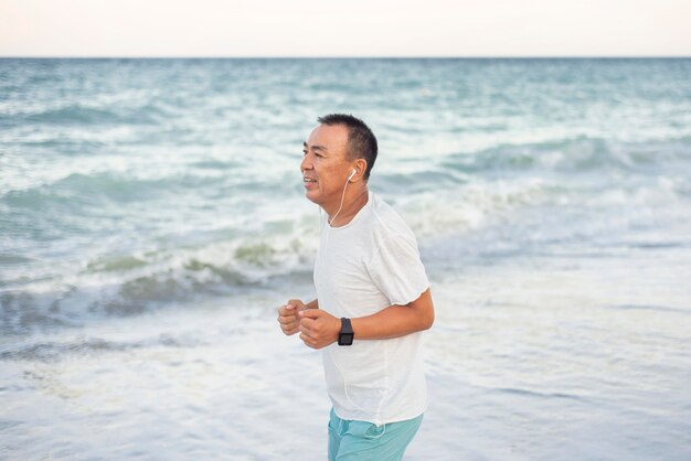 Uomo di vista laterale che corre sulla spiaggia