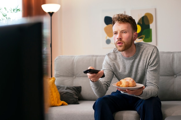 Uomo di vista laterale che guarda le notizie in tv