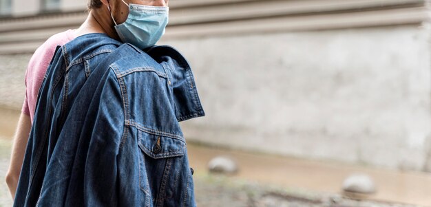 Uomo di vista laterale che indossa una maschera medica all'aperto con lo spazio della copia