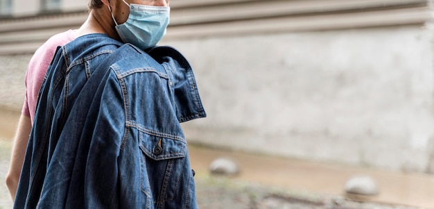 Uomo di vista laterale che indossa una maschera medica all'aperto con lo spazio della copia