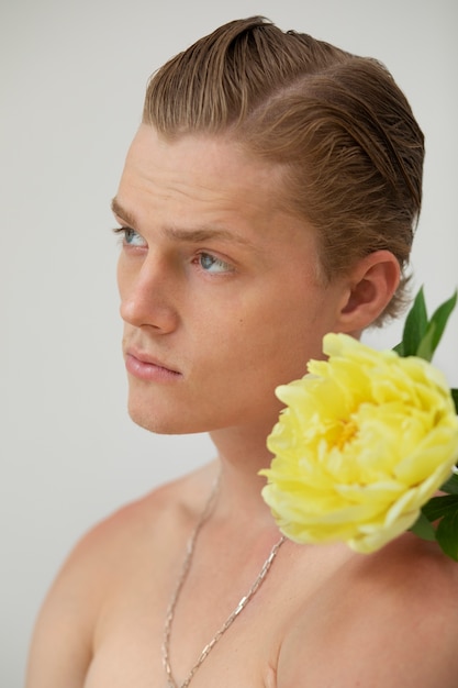 Uomo di vista laterale che posa con il fiore in studio