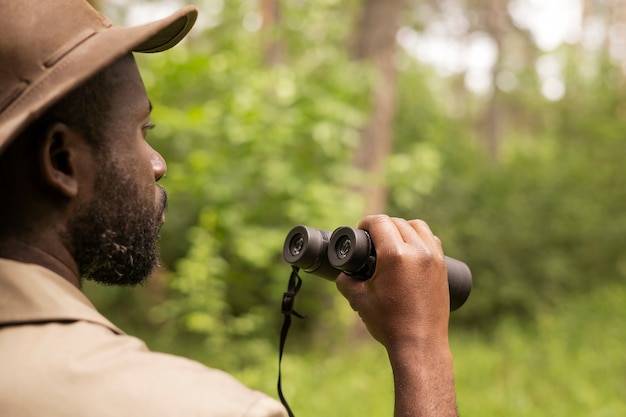 Uomo di vista laterale che tiene il binocolo