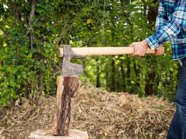 Uomo di vista laterale che usando un'ascia per tagliare legno