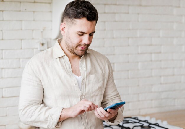 Uomo di vista laterale con il telefono in cucina