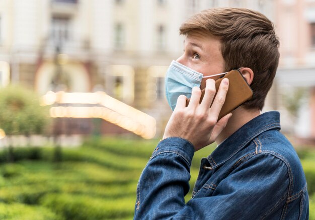 Uomo di vista laterale con maschera facciale che guarda lontano